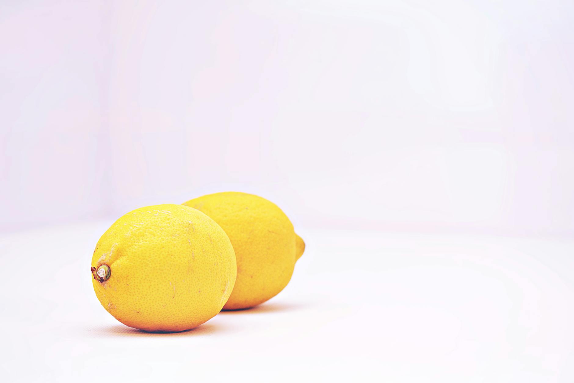 Close-up of a hand holding an orange vibrator against a minimalistic purple backdrop