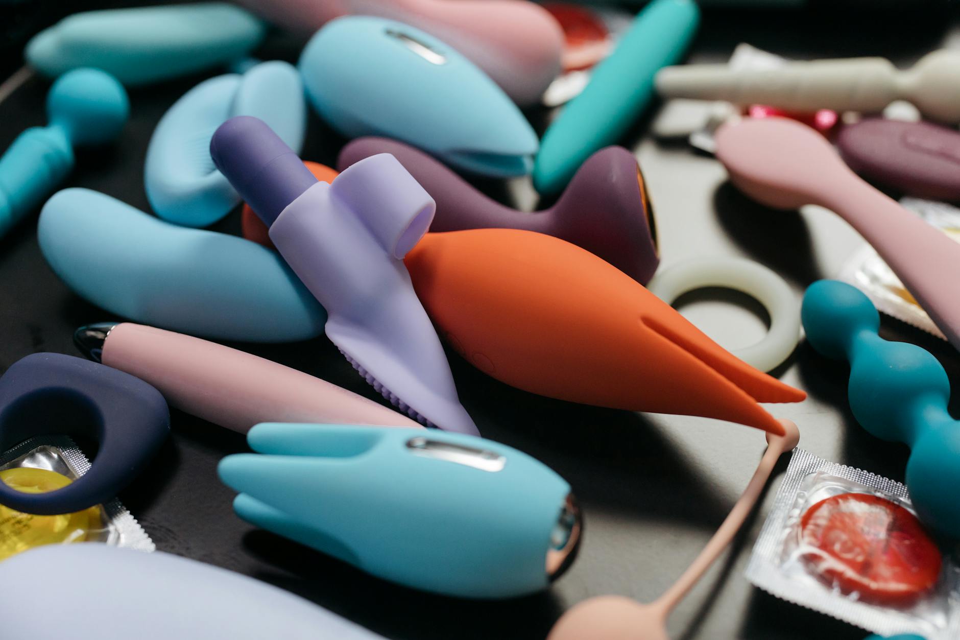 A hand holding a modern clitoral vibrator against a minimalist purple backdrop